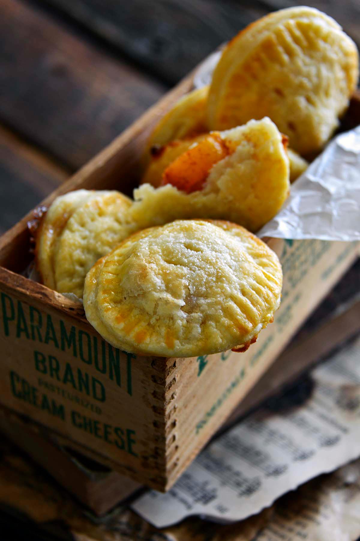 front view of flaky peach hand pies on wooden box