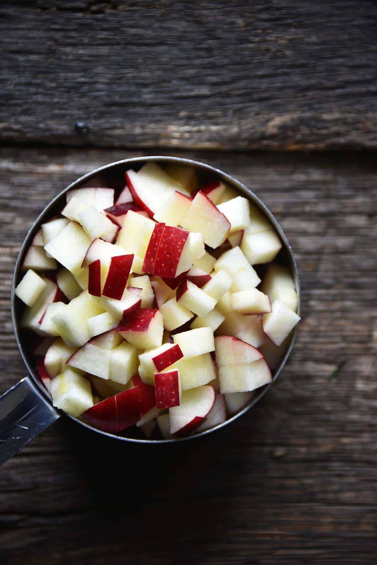 chopped apple in measuring cup for making chutney sauce