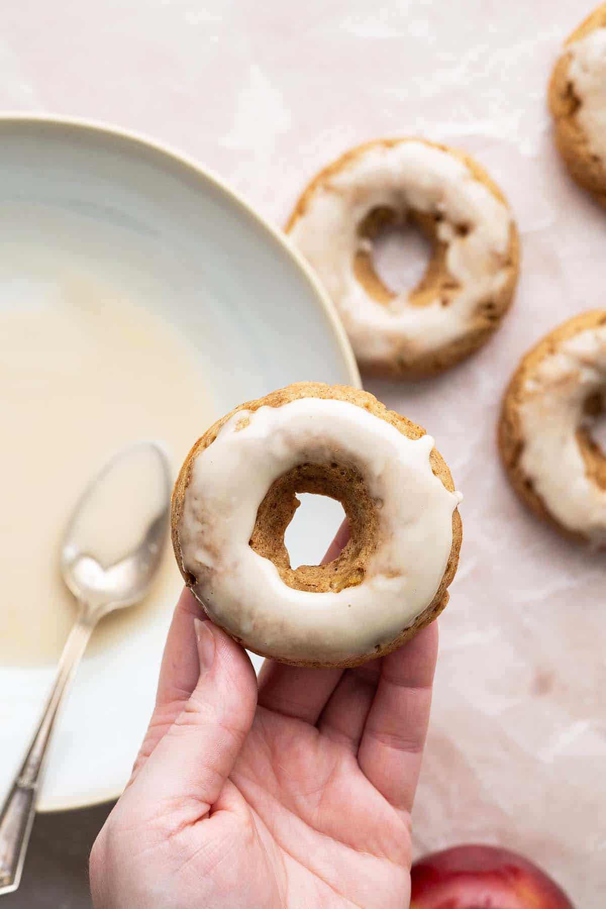 dipping apple donuts in vanilla glaze