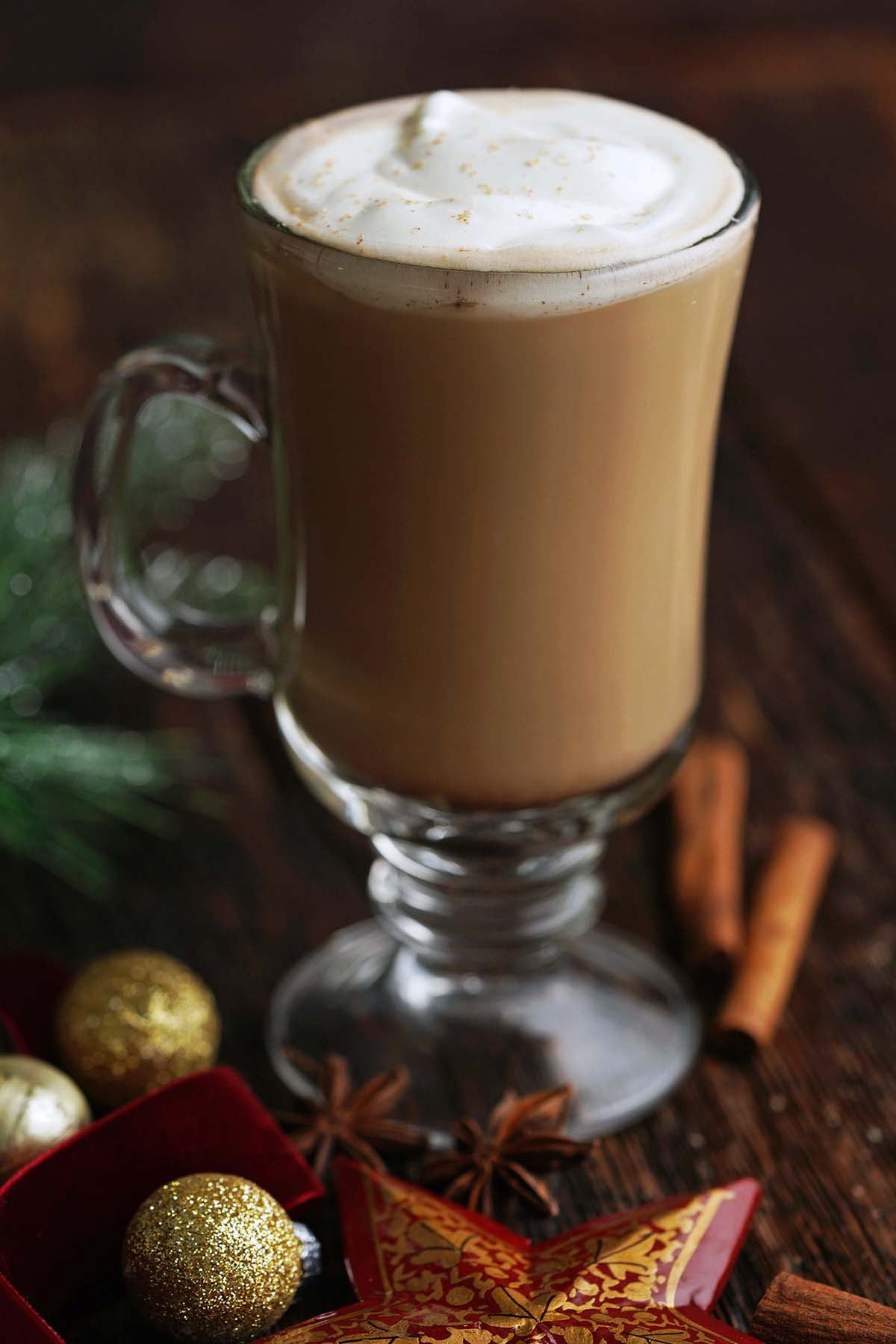 close up front view gingerbread latte in glass mug on table with Christmas ornaments for decoration