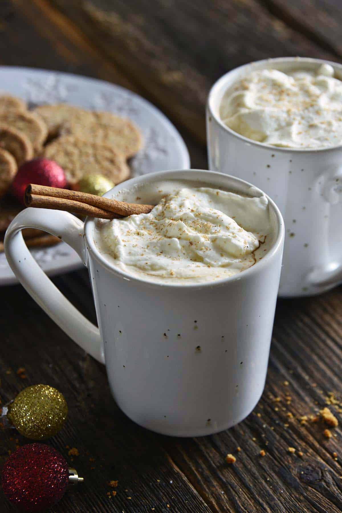 eggnog lattes in mugs garnished with whipped cream and nutmeg