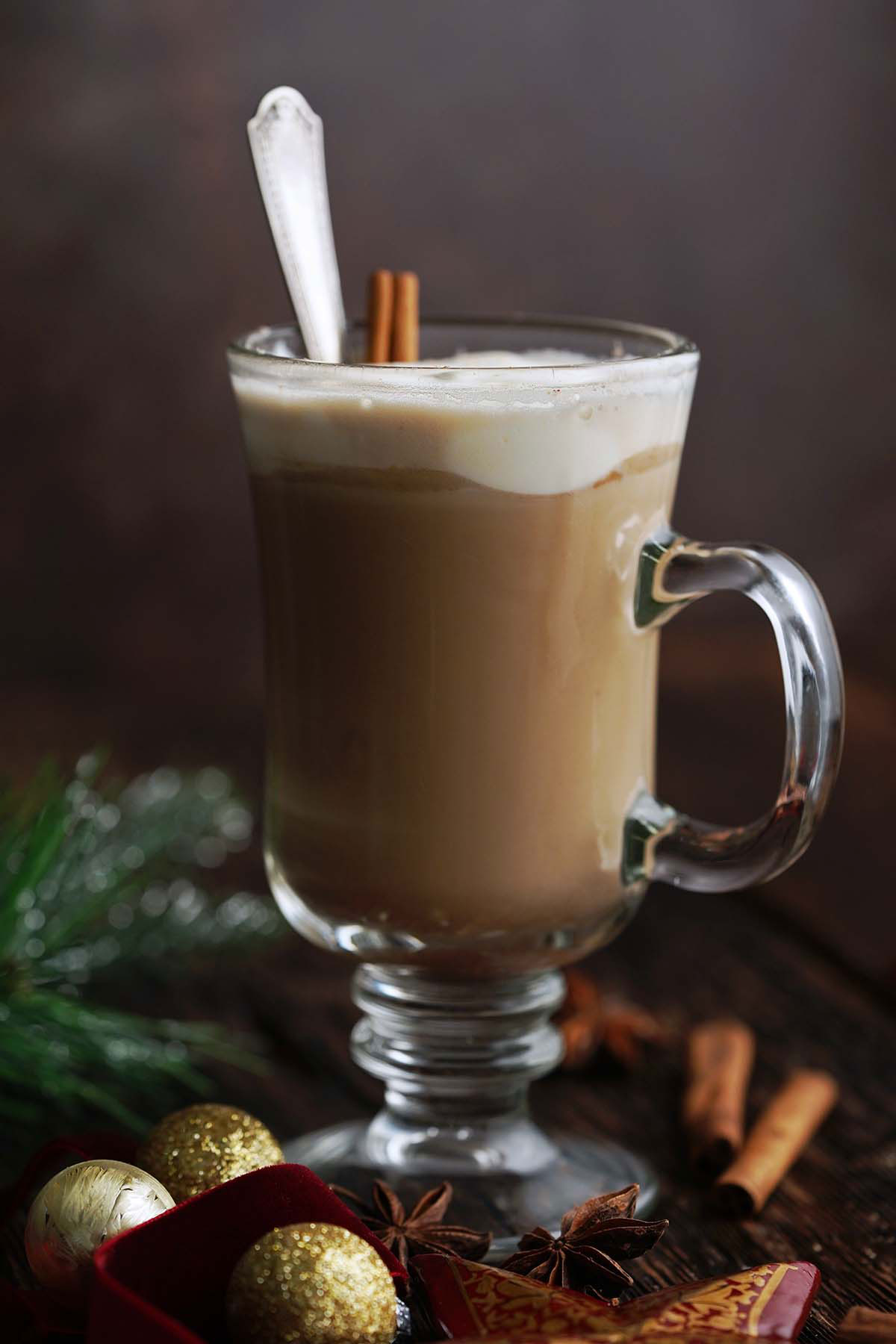 festive gingerbread coffee latte with Christmas ornaments around on wooden table