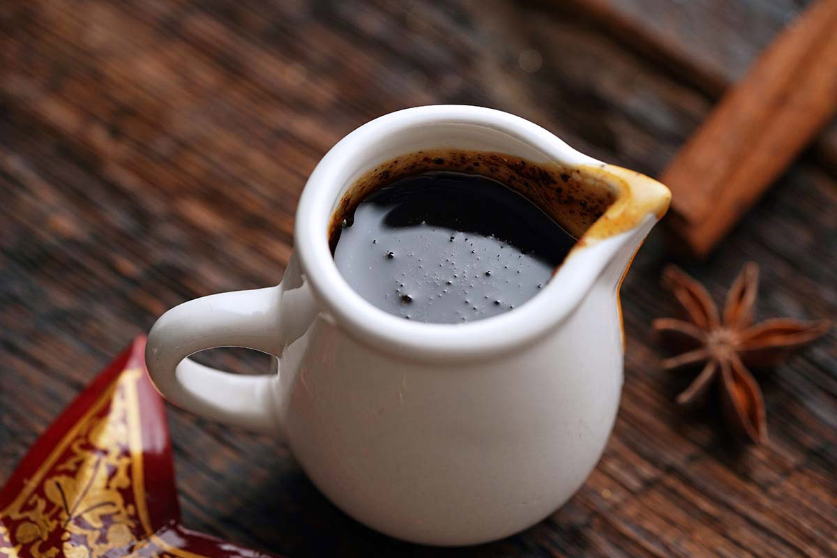 small white pitcher of gingerbread simple syrup on wooden table