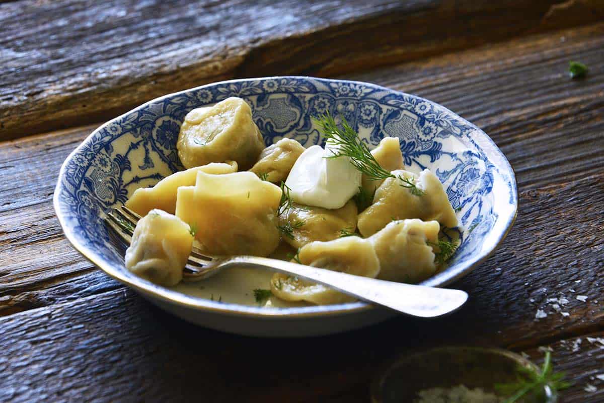 bowl of russian dumplings topped with sour cream and dill