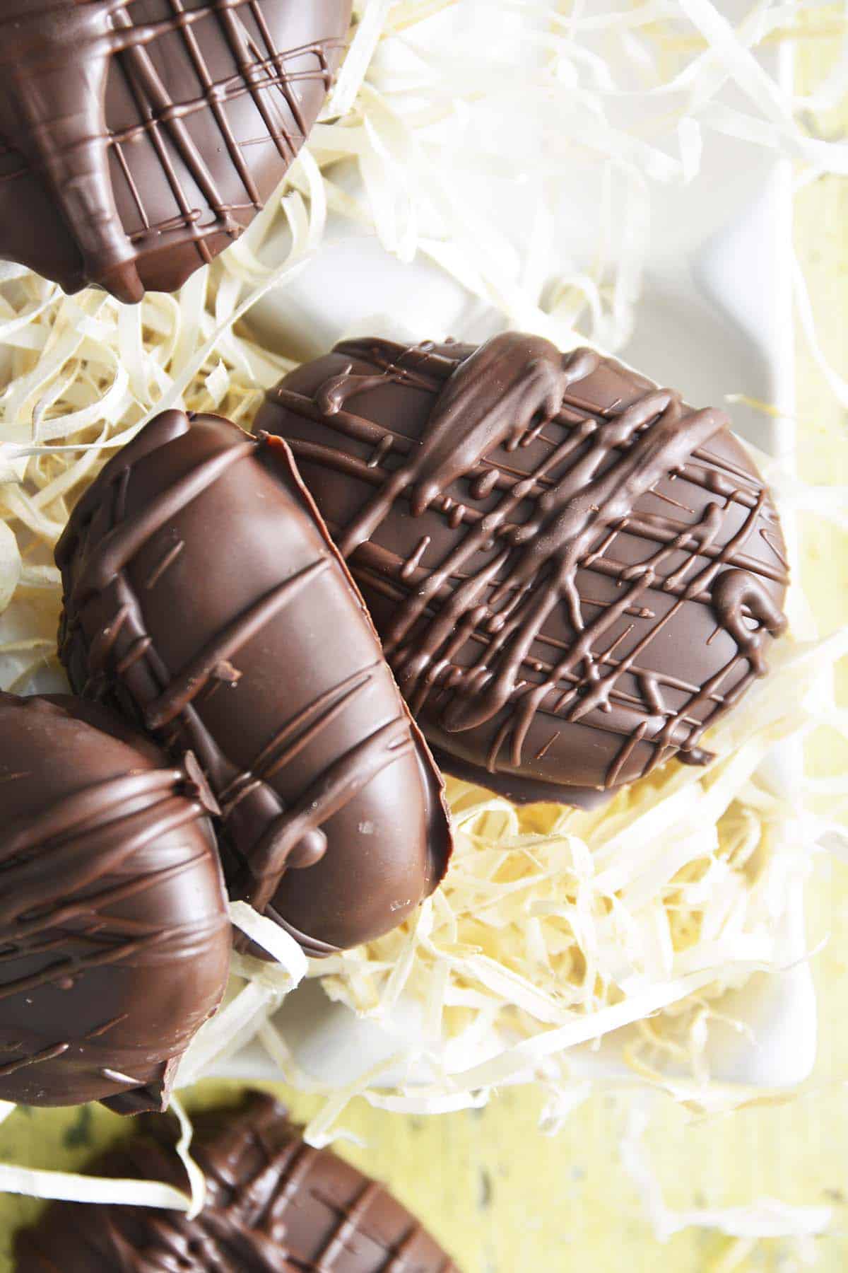 easter peanut butter eggs on straw on yellow wooden table