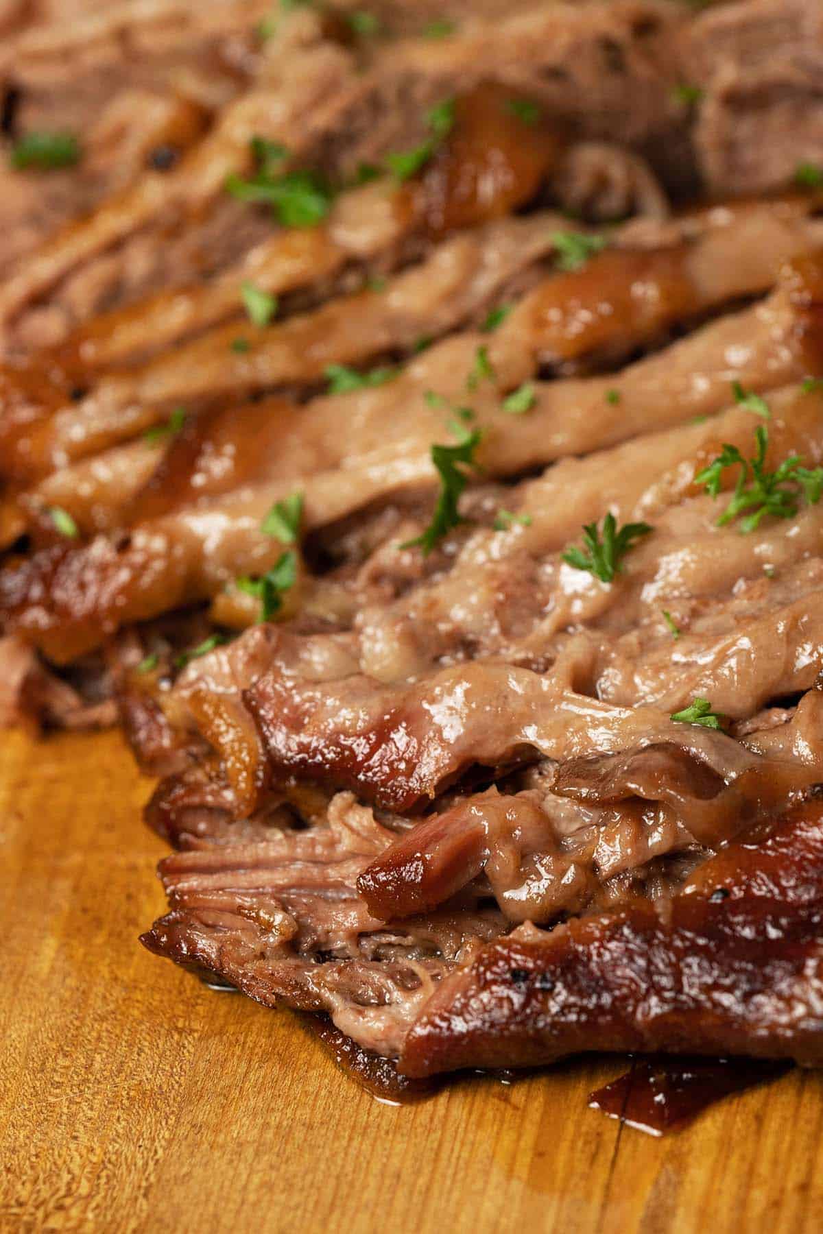 front view of classic juicy beef brisket sliced on cutting board