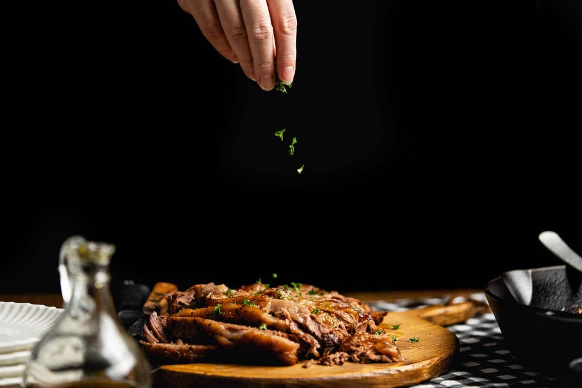 sprinkling parsley on top of brisket