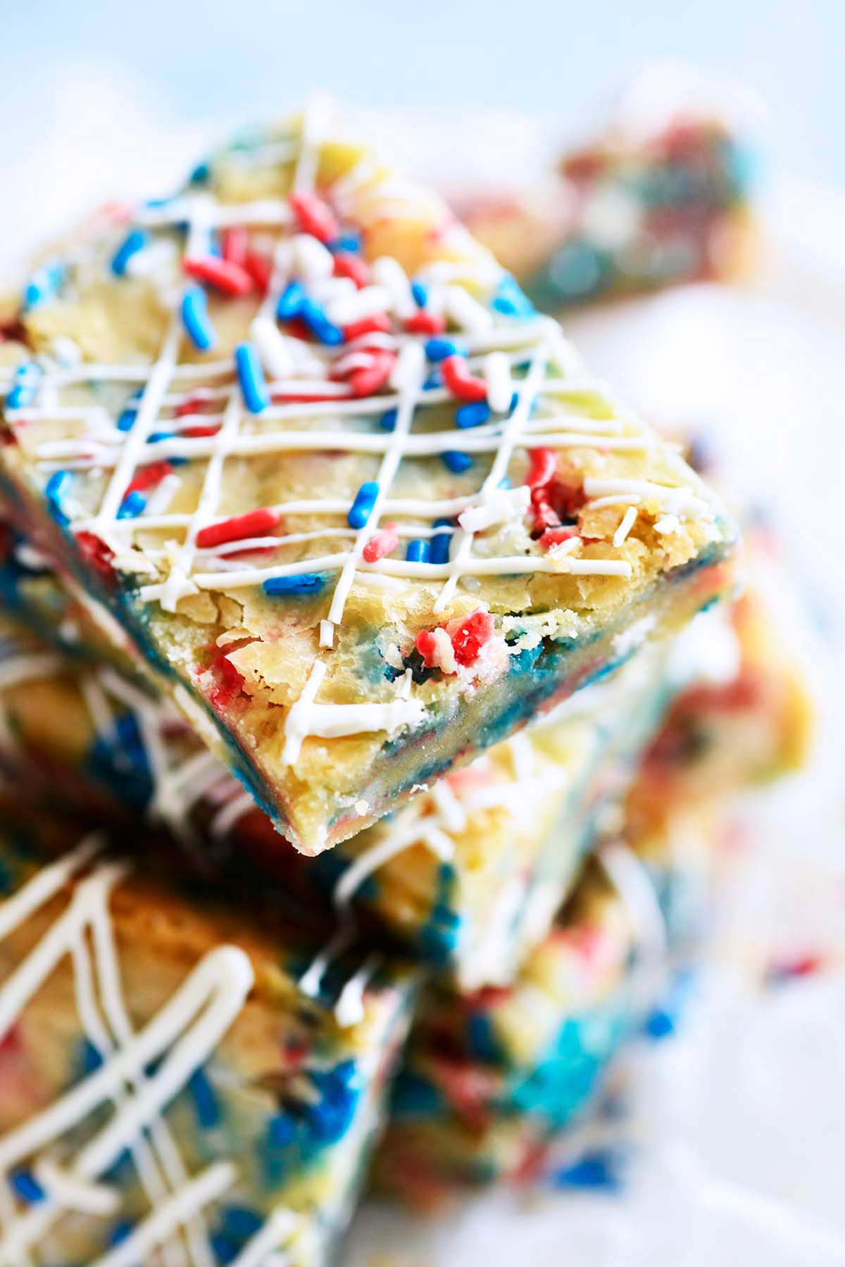 stack of gooey funfetti blondie cookie bars with red white and blue sprinkles