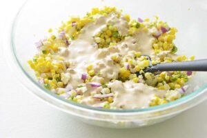 elotes with creamy dressing before stirring