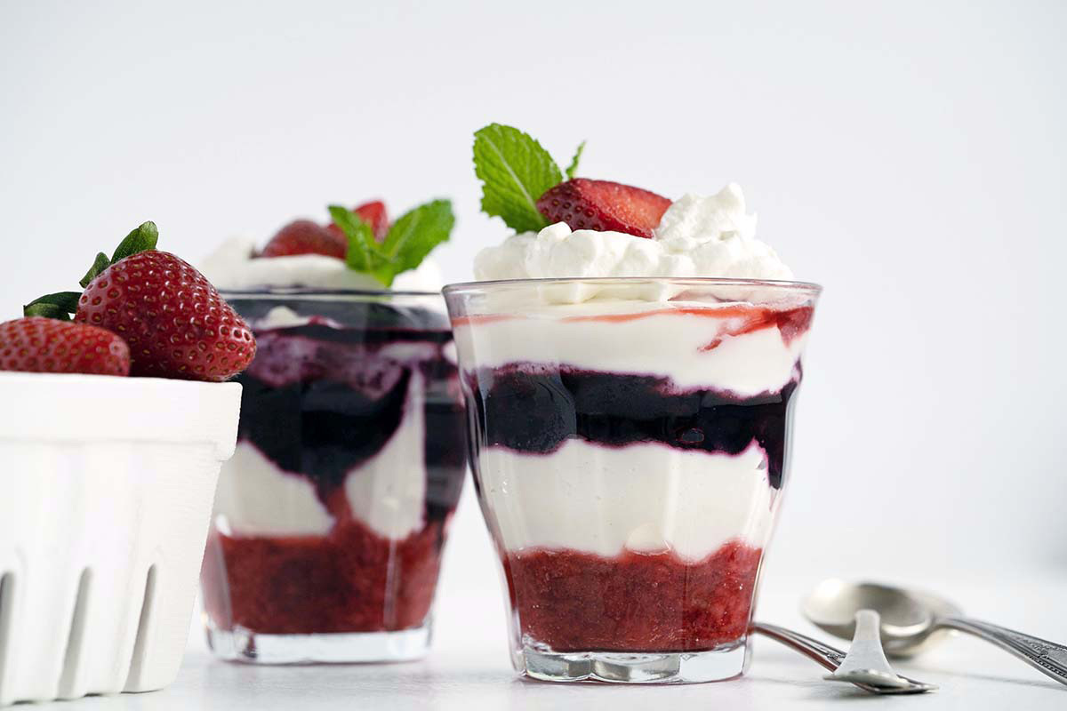front view of patriotic cheesecake parfaits with basket of fresh strawberries