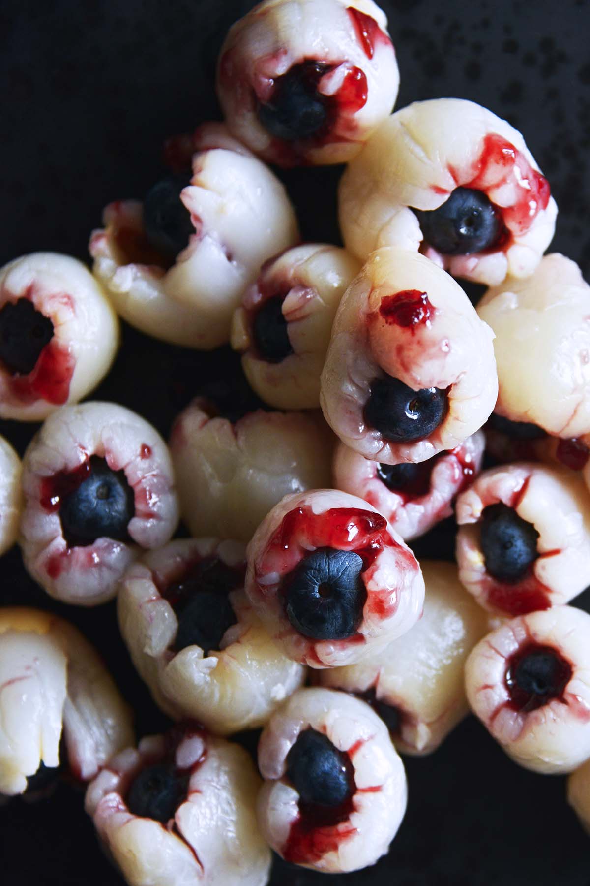 close up top view of edible bloody halloween eyeballs on black plate