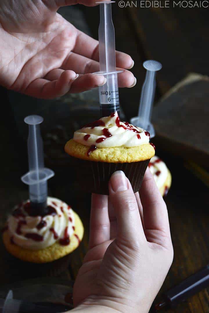 injecting edible fake blood with syringe into cupcake