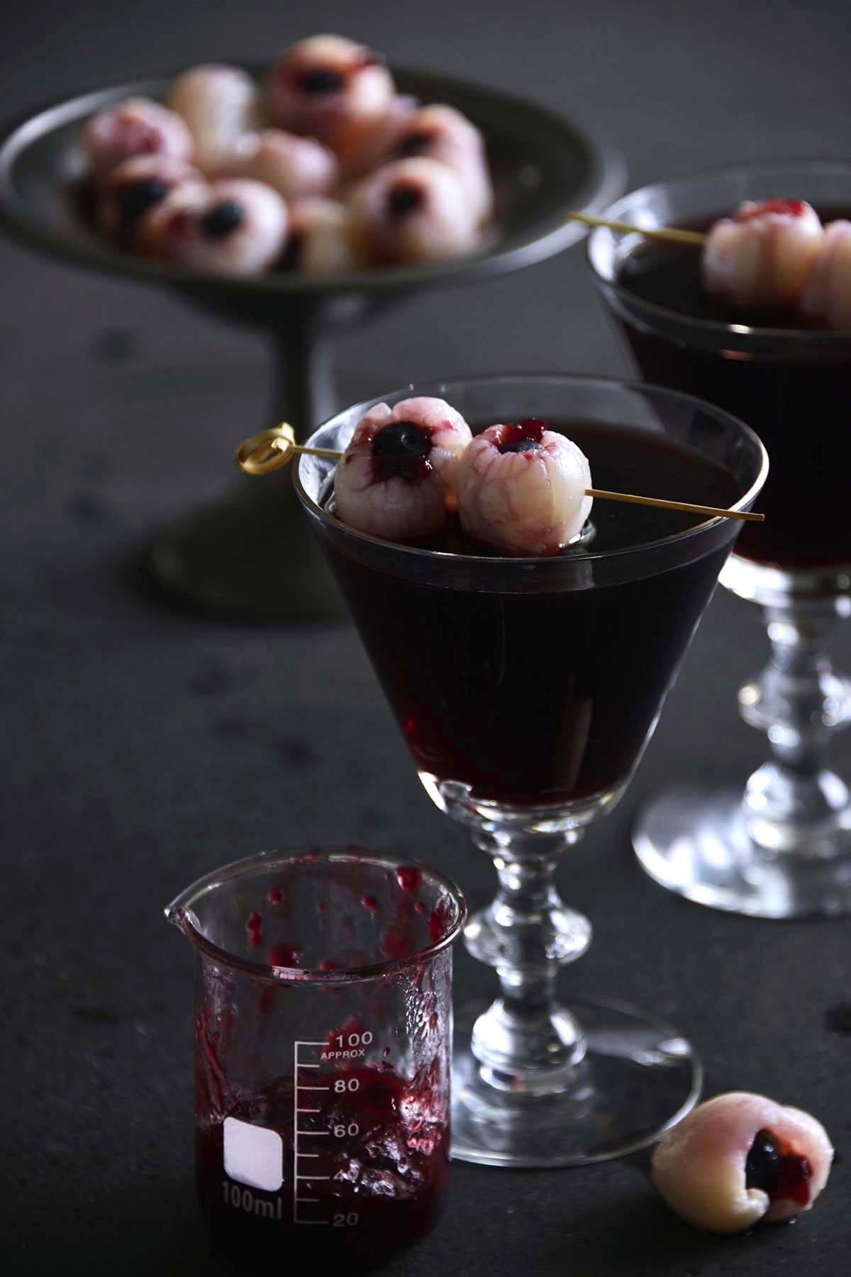 red wine cocktail with edible bloodshot eyeballs on black table