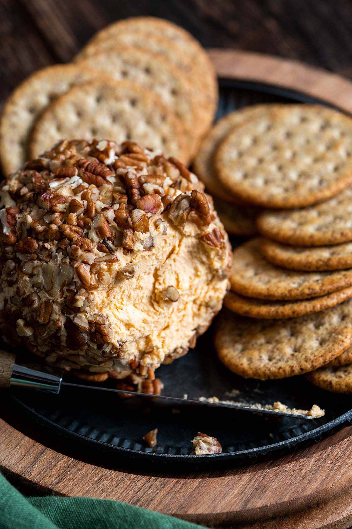 front view of cheddar cheeseball on platter with crackers