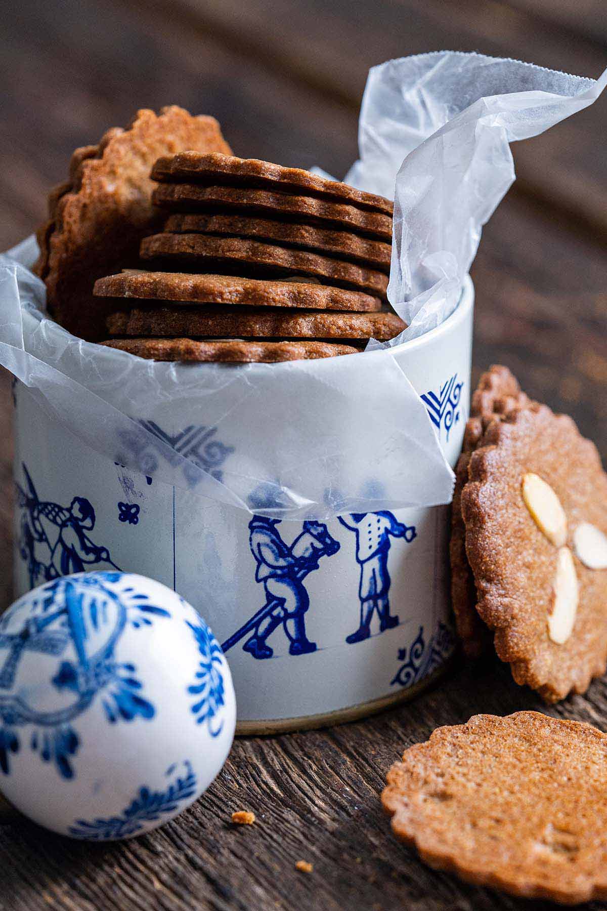 stack of thin Speculaas cookies with almonds in blue and white Dutch cookie tin