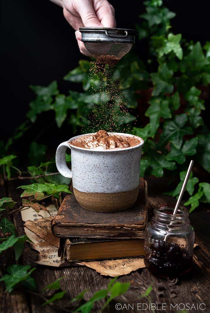 shaking cocoa powder onto hot chocolate