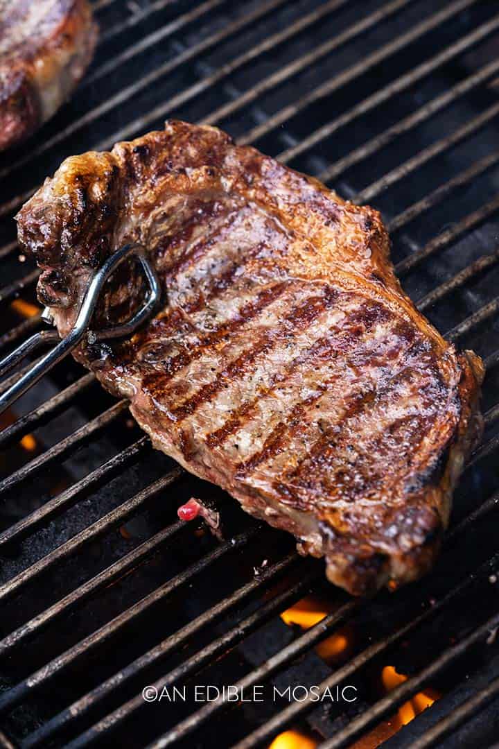 flipping ribeye steak on the grill