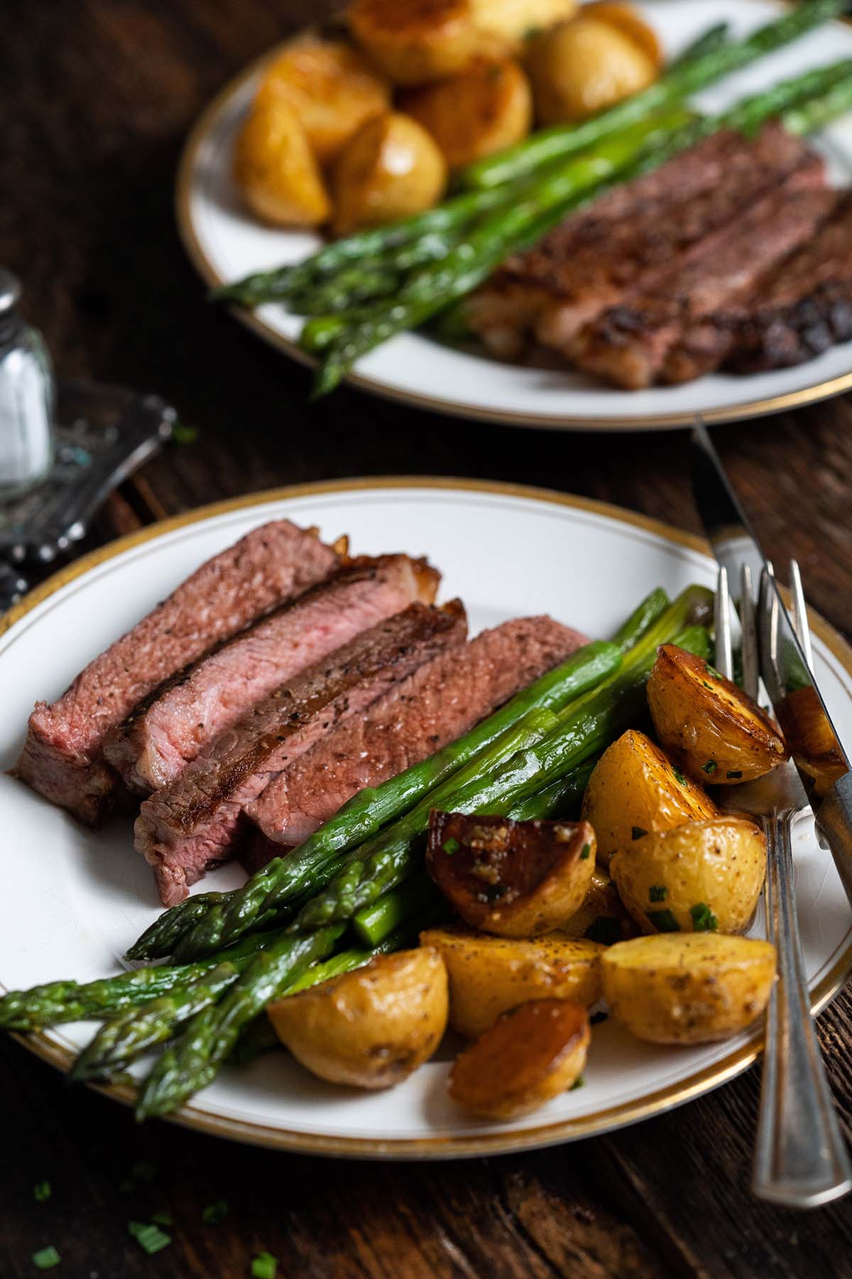 front view of 2 plates of ribeye dinner with vegetables