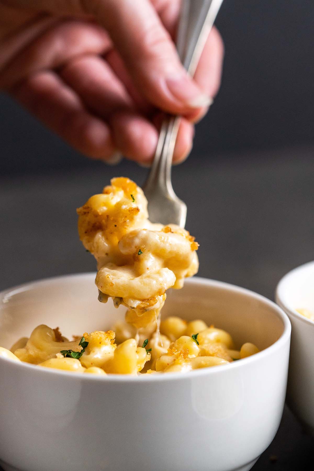 hand holding fork with cheese pull from mac and cheese