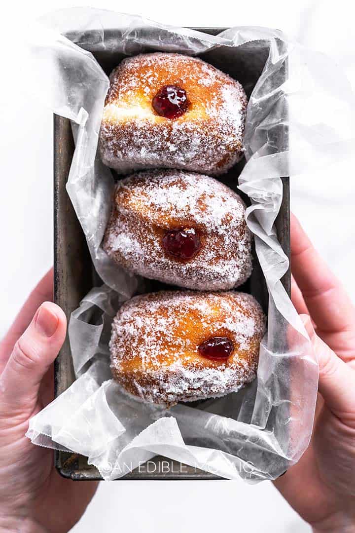 hands holding dish with 3 jelly donuts