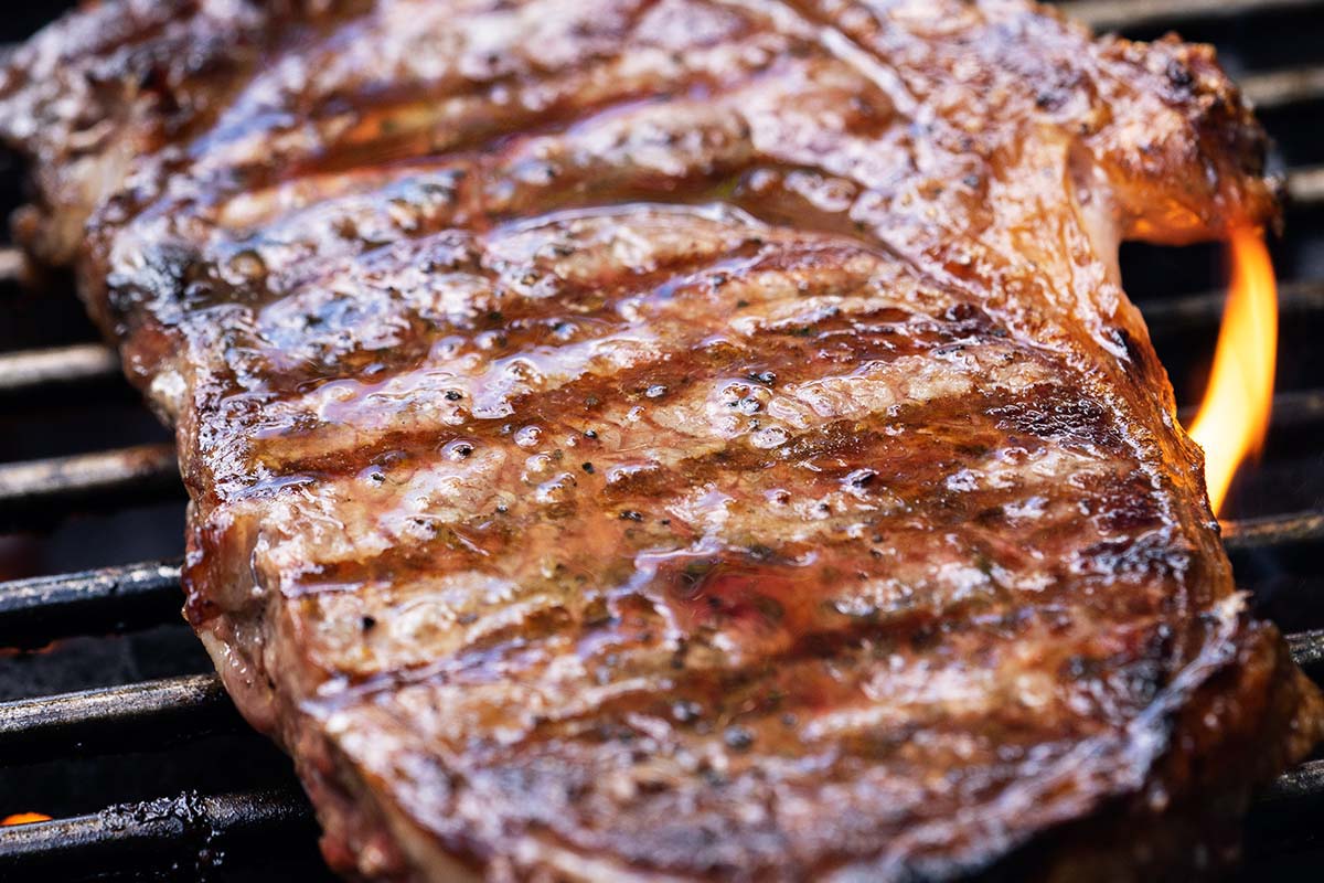 ribeye steak on gas grill with flames