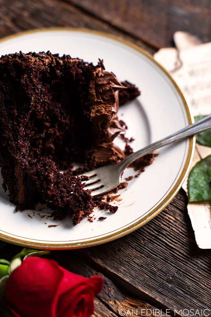 slice of chocolate layer cake on white plate with bites removed