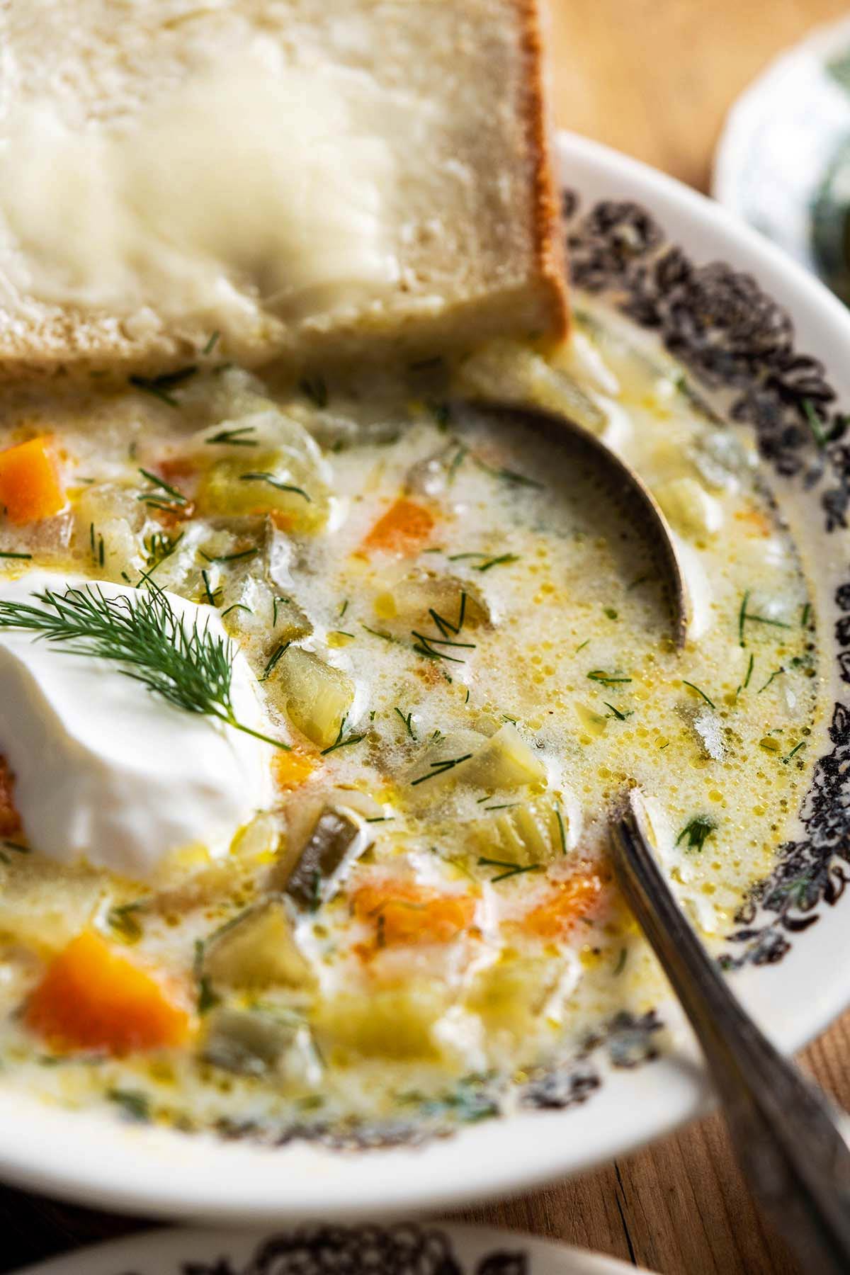 close up of vintage bowl with creamy cucumber soup with buttered bread