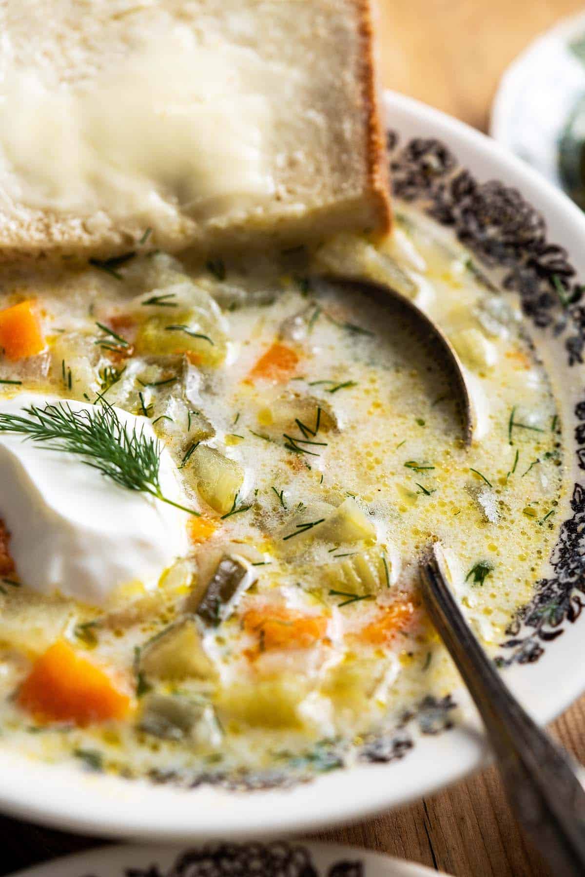 close up of vintage bowl with creamy cucumber soup with buttered bread