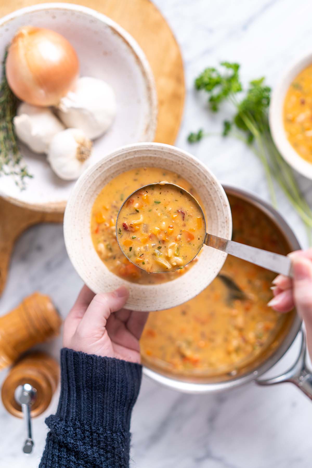 ladling tuscan white bean bisque soup into bowl
