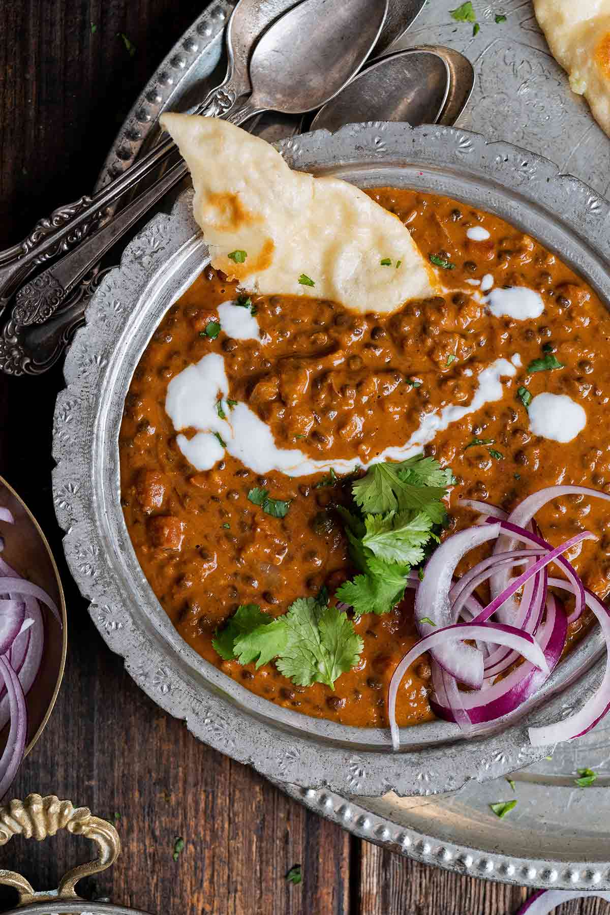 overhead view of dal makhani with naan in Indian serving bowl