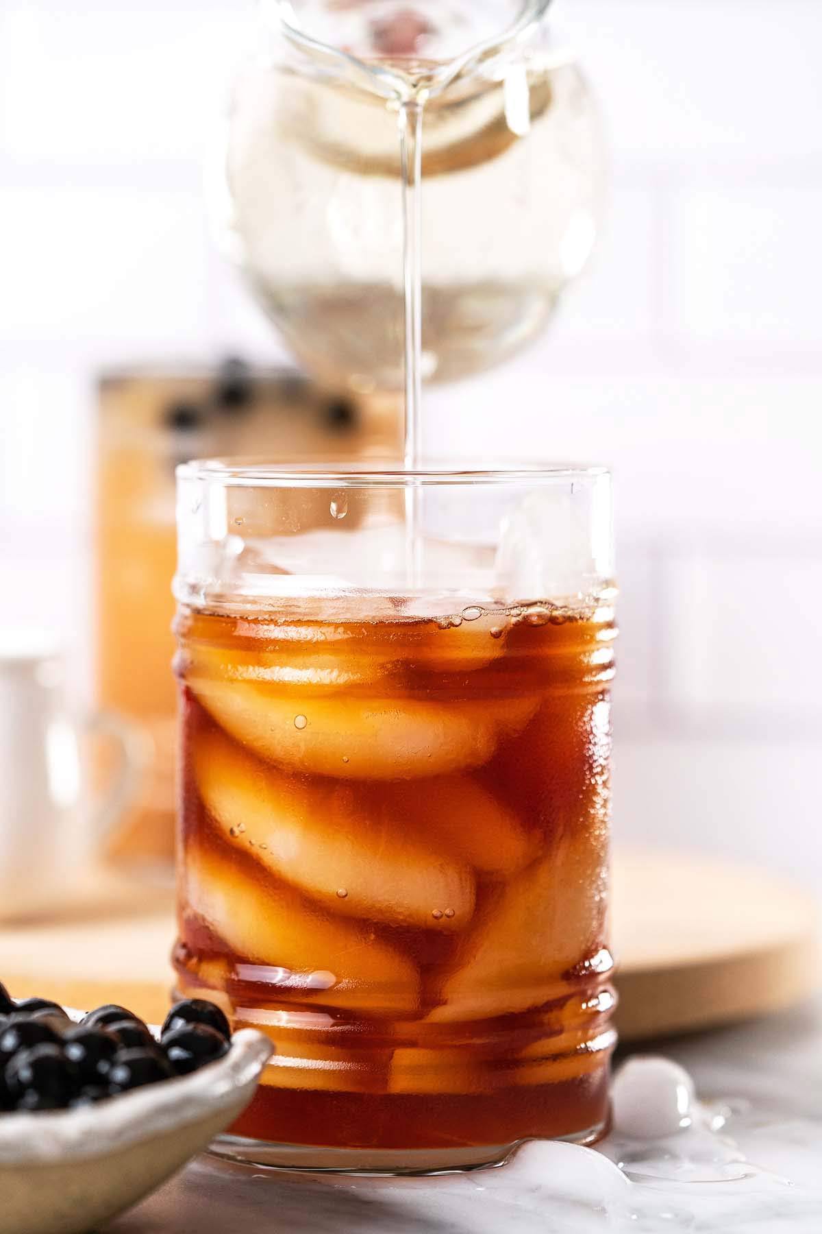 pouring simple sugar syrup into iced tea glass