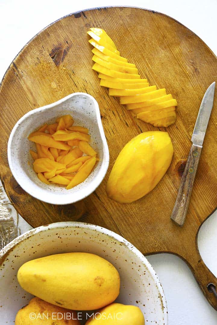 slicing mango on wooden cutting board