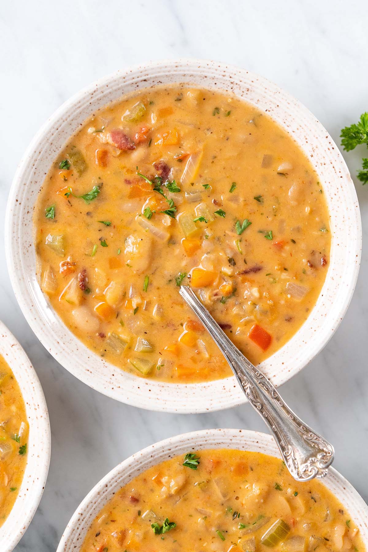 top view of creamy cannellini bean soup in stoneware bowls on marble countertop