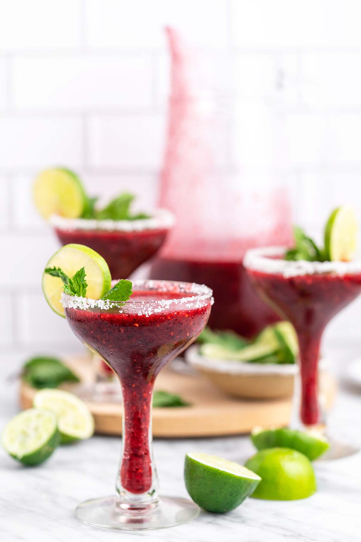 berry margaritas in glasses with pitcher in background
