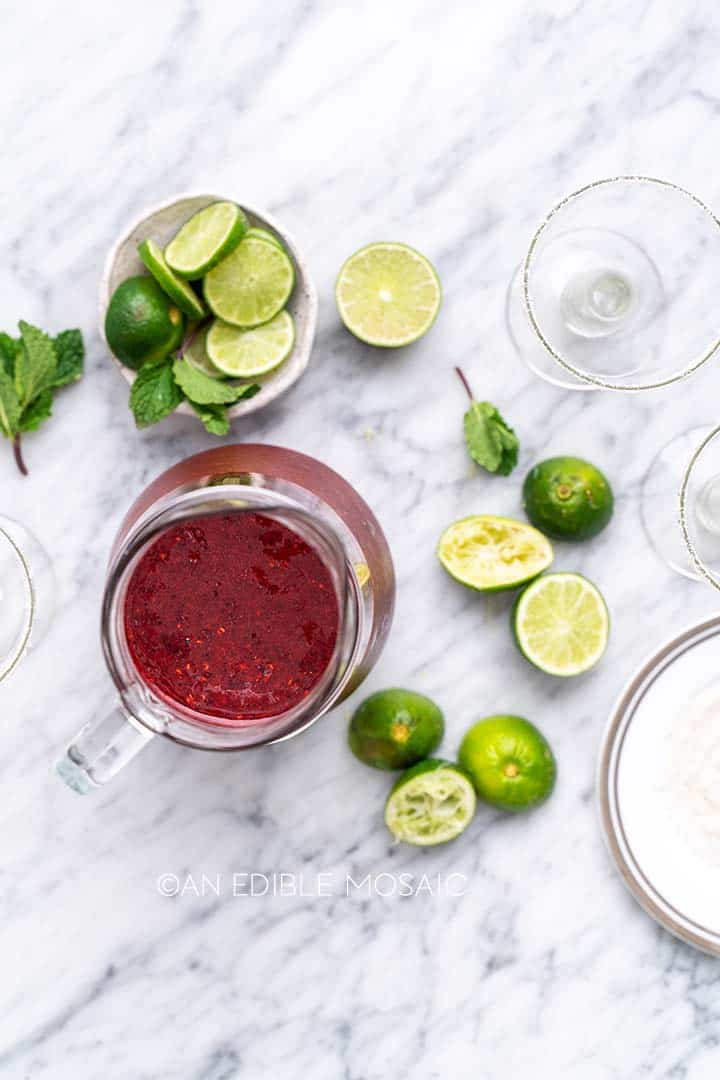 pitcher of mixed berry margaritas with limes