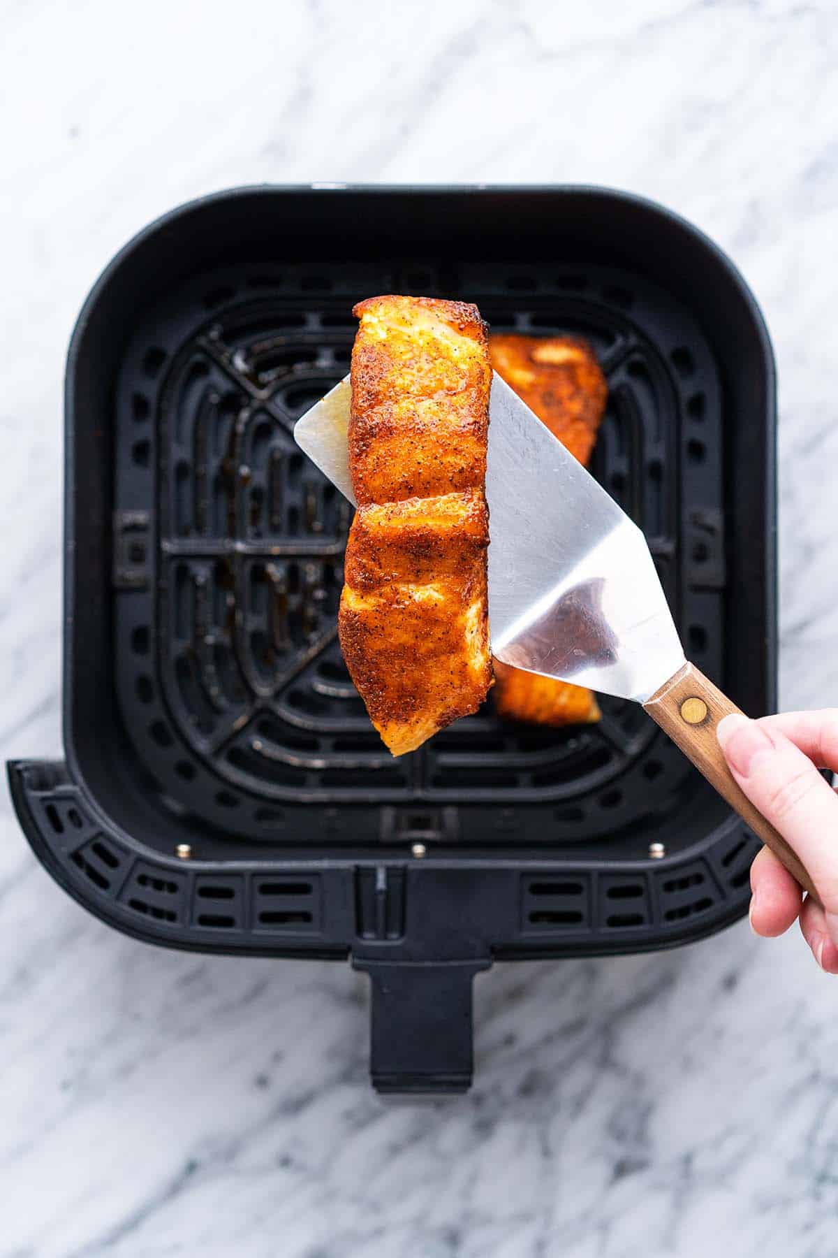 hand holding spatula with cooked salmon filet