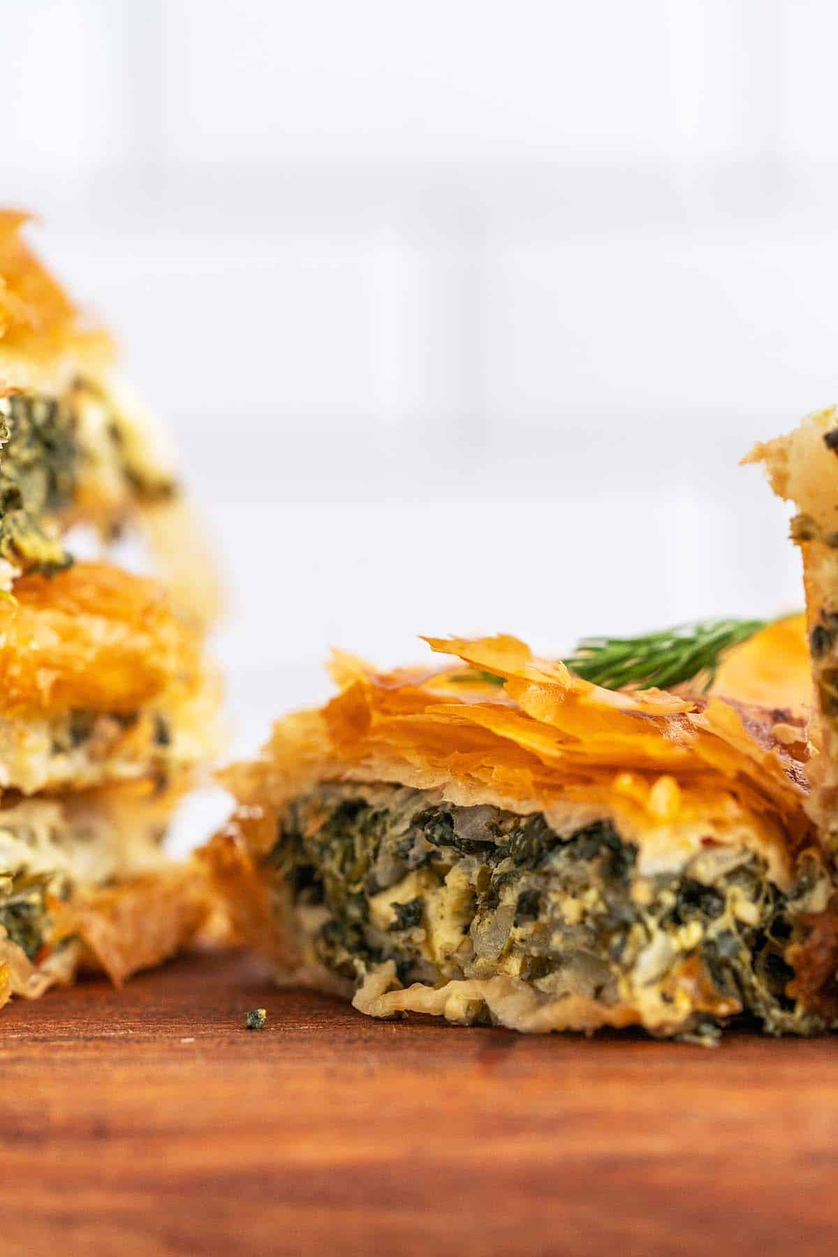 slice of spinach pie with filo on wooden cutting board