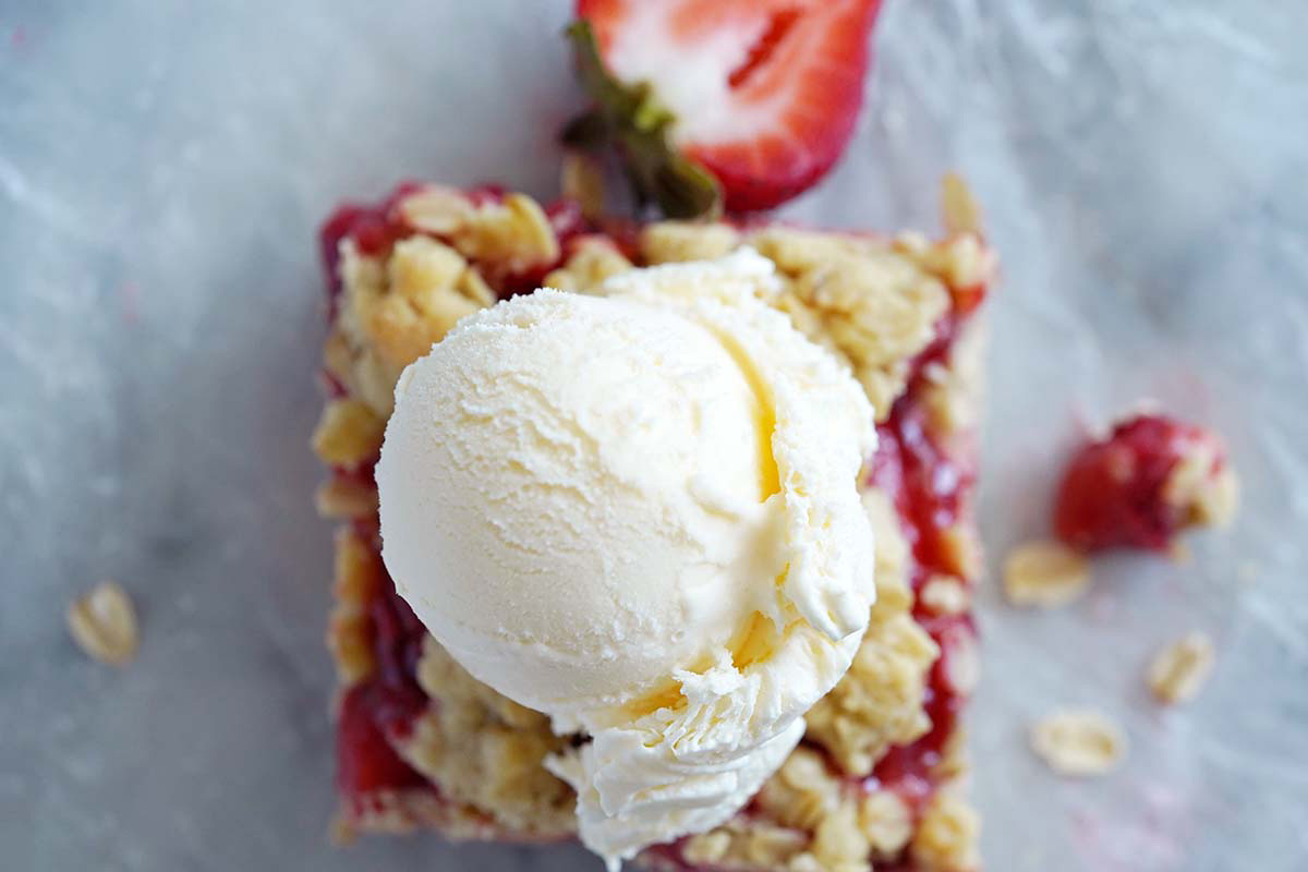 top view of strawberry oat cookie bar topped with scoop of vanilla ice cream