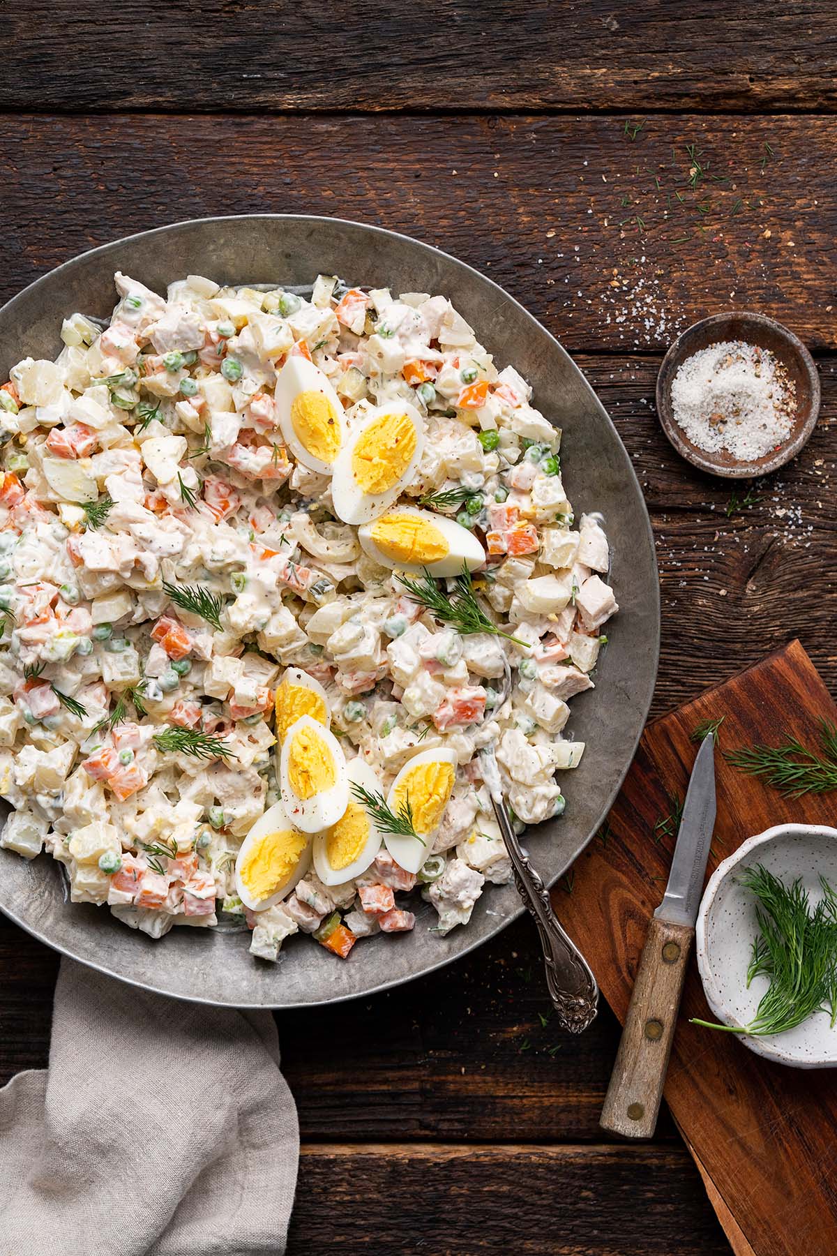 platter of russian salad olivieh on dark wooden table