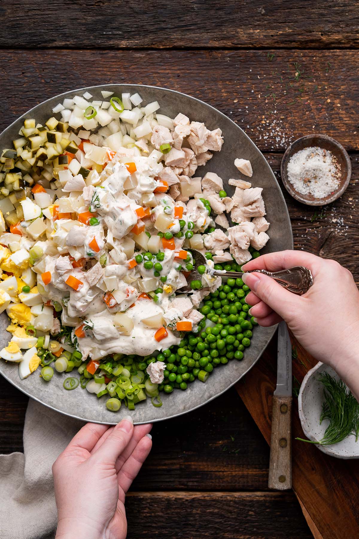 stirring creamy mayo based dressing into russian potato salad