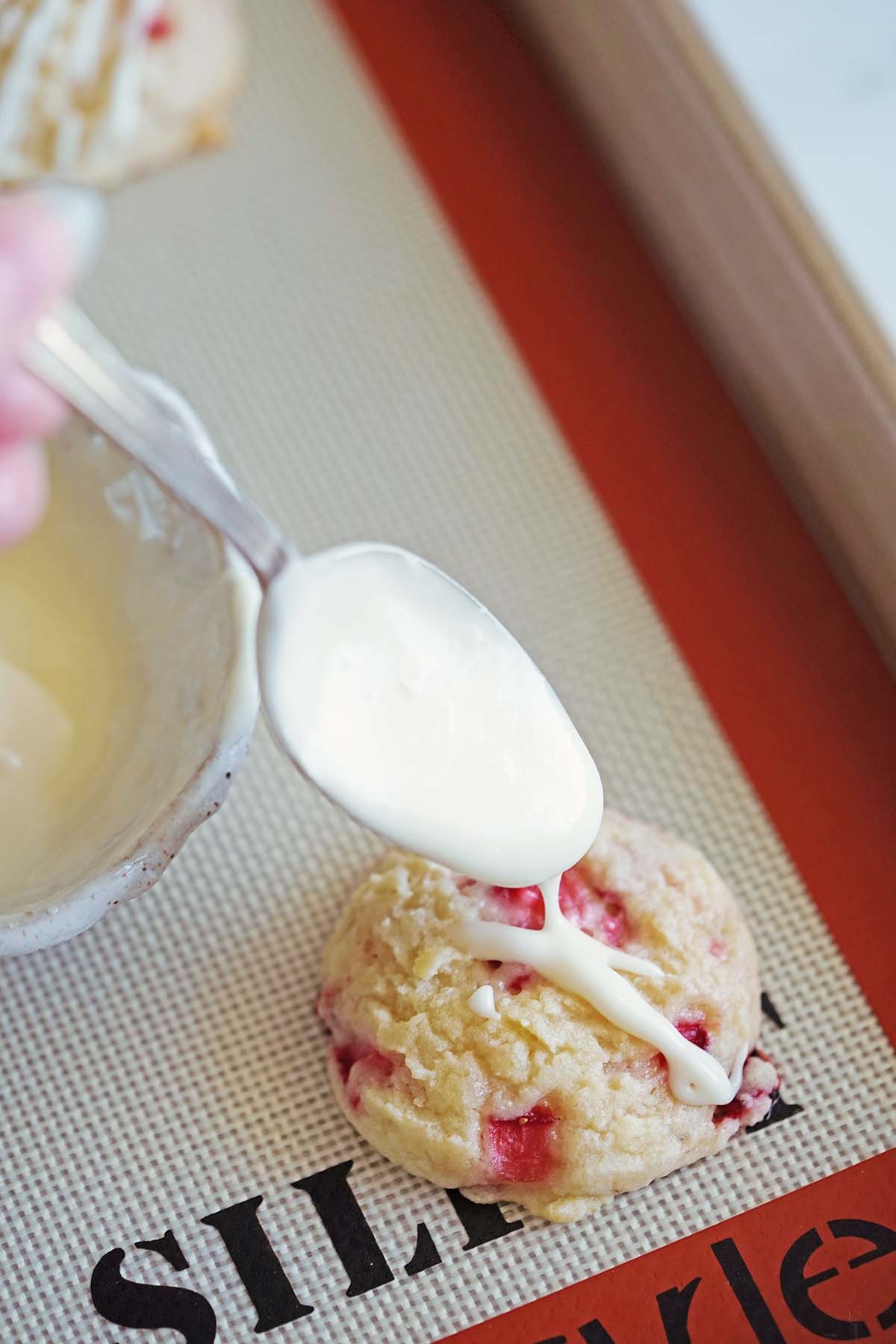 hand drizzling icing off spoon onto cookie