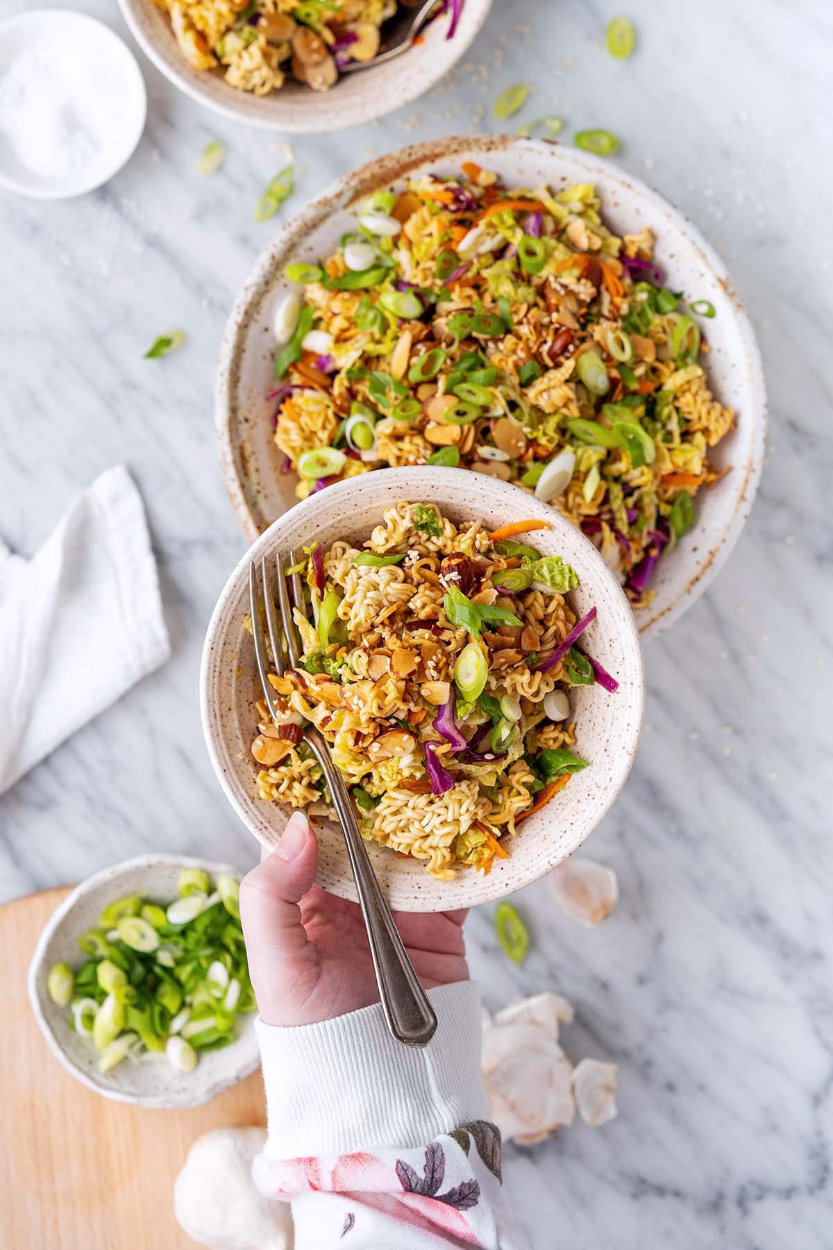 hand holding bowl of crunch salad made with ramen noodles and cabbage
