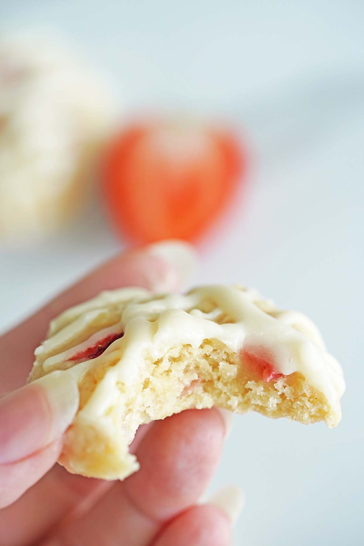 hand holding strawberry cookie with bite to show chewy inside