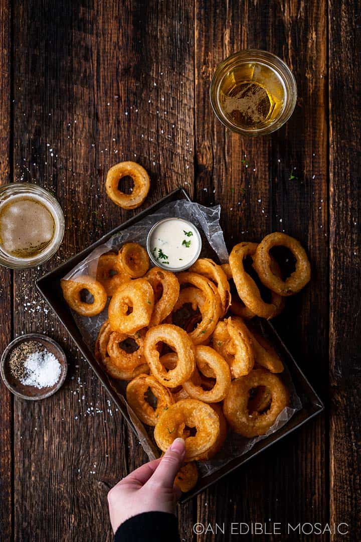 hand reaching in to grab onion ring off platter