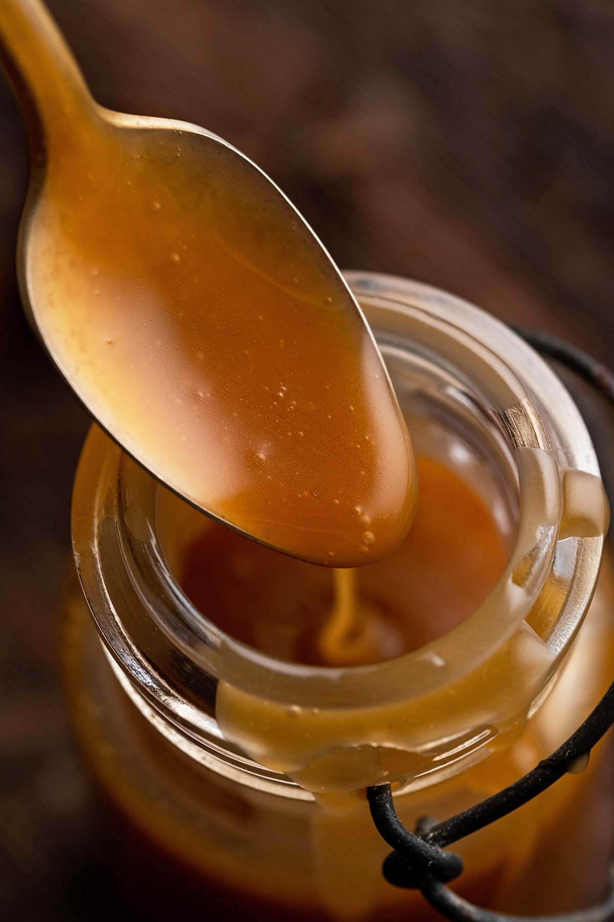 spoon with swirl of homemade butterscotch dripping off into jar