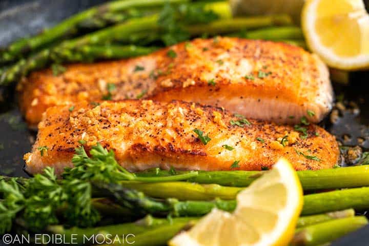 cooked salmon in skillet with asparagus and lemon