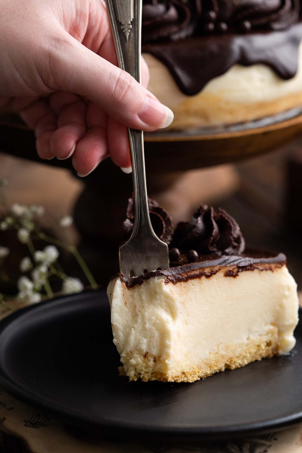 hand holding fork taking a bite of a slice of creamy mousse cake