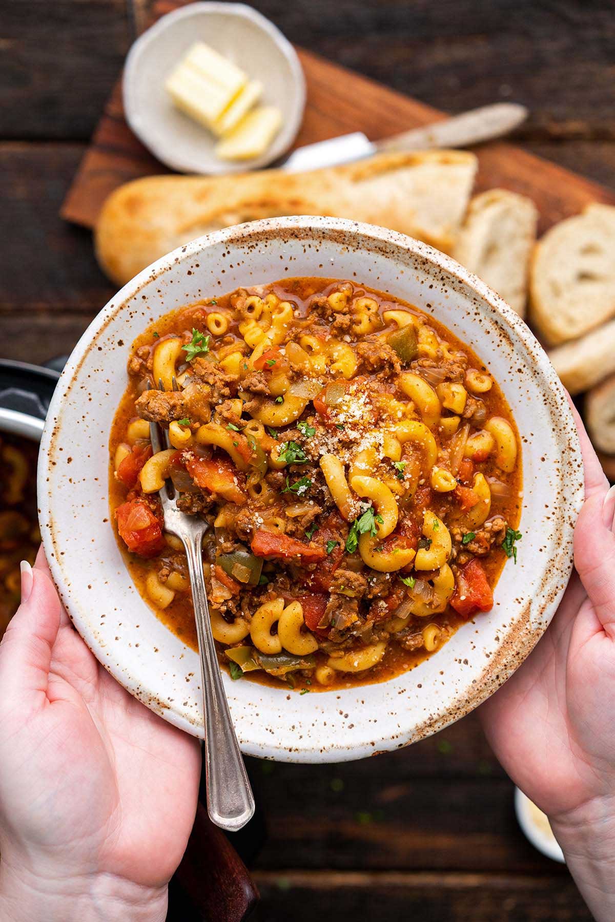 hands holding stoneware bowl with easy American ground beef goulash