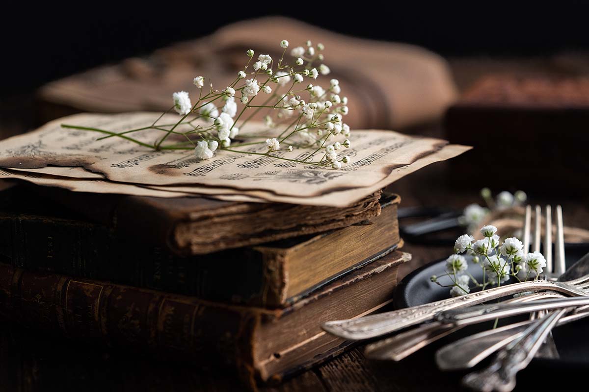 pile of vintage books with baby's breath flowers and vintage forks and silverware