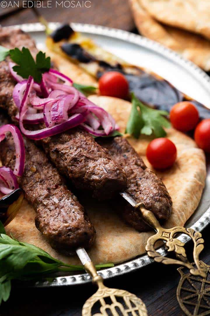 platter of ground lamb kebabs on flatbread with vegetables